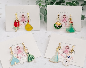 May include: Four pairs of princess-themed earrings displayed on white cards. Each pair features a different princess character, including Belle, Ariel, Elsa, and Anna. The cards have the text "Handmade with Lots of Love" and "by Mo Kids Accessories".