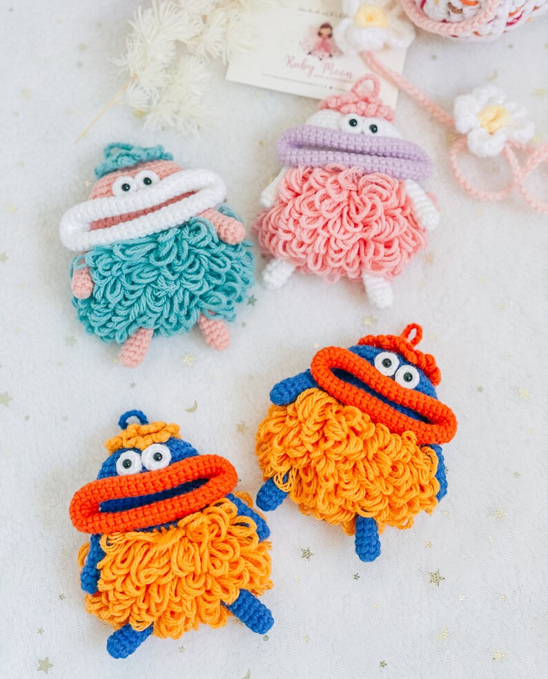 Puede incluir: Cuatro juguetes de peluche tejidos a crochet con diferentes colores de pelo y rasgos faciales. Los juguetes tienen ojos grandes, una boca y una m&aacute;scara de crochet blanca. Los juguetes son de varios colores, incluyendo azul, naranja, rosa y verde.