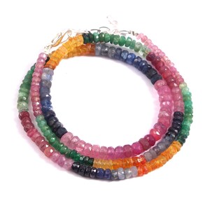 Pode incluir: Um colar de pedras preciosas multicoloridas com contas rosa, vermelho, verde, azul e laranja. O colar é feito de pedras preciosas facetadas e é enfiado em uma corrente de prata.