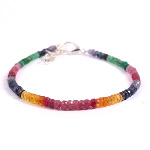 May include: A rainbow gemstone bracelet with a silver clasp. The bracelet features a variety of gemstones, including blue sapphires, green emeralds, red rubies, and orange citrines.
