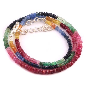 May include: A multi-colored gemstone necklace with a silver clasp. The necklace features red, blue, green, and yellow gemstones.