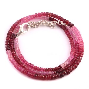 May include: A multi-strand necklace made of pink and red gemstone beads. The necklace has a silver clasp.