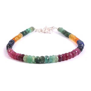May include: A multi-colored gemstone bracelet with a silver clasp. The bracelet features a rainbow of colors, including red, orange, yellow, green, blue, and purple.