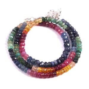 Puede incluir: Un collar de piedras preciosas multicolores con cuentas en tonos azules, verdes, rojos y amarillos. El collar está hecho de cuentas facetadas y tiene un cierre plateado.