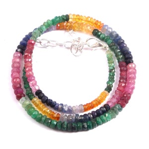 May include: A multi-colored gemstone necklace with a silver clasp. The necklace features beads of pink, red, blue, green, and yellow gemstones.