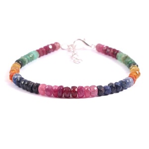 May include: A rainbow gemstone bracelet with a silver clasp. The bracelet features a variety of colors, including red, orange, yellow, green, blue, and purple.