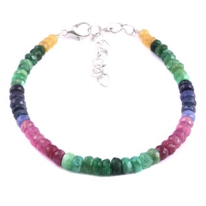 Puede incluir: Un brazalete de piedras preciosas multicolores con un cierre de plata. El brazalete presenta un degradado de colores, comenzando por el amarillo, luego el verde, el azul, el rosa y terminando con el verde de nuevo.