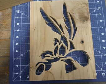 May include: A wooden cutout of the cartoon character Wile E. Coyote from the Looney Tunes series. The cutout is on a blue and white grid background.