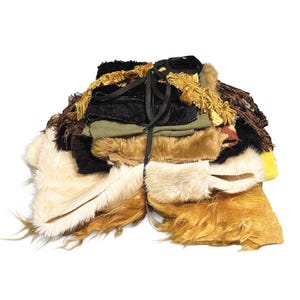 May include: A bundle of assorted fabric scraps including black velvet, olive green cloth, and textured faux fur in shades of cream, tan, and brown. The collection is tied together with a black ribbon and features decorative gold fringe trim.