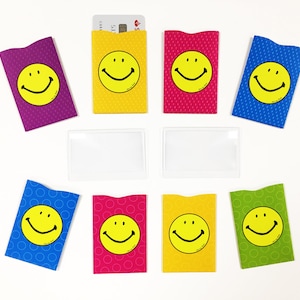 May include: Nine colorful card holders with a smiley face design. The card holders are made of a soft, flexible material and are perfect for protecting credit cards, debit cards, and other important documents.