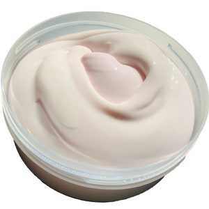 Pu&ograve; includere: Primo piano di una crema bianca e rosa in un contenitore di plastica trasparente. La crema &egrave; liscia e ha un motivo a spirale.