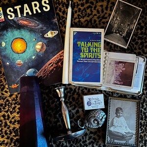 Antique mystery box, gothic style with oddities and creepy photos, occult book and candles.