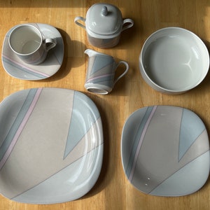May include: A set of grey and white ceramic dinnerware with geometric patterns. The set includes a large bowl, two plates, a creamer, a sugar bowl, and a mug.