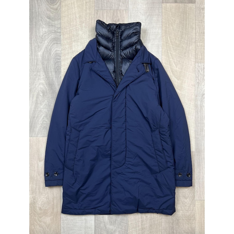 May include: A navy blue, long coat with a quilted black collar. The coat has a button closure and two side pockets. The coat is made of a lightweight material and is suitable for cooler weather.