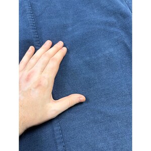 May include: A solid dark blue fabric garment featuring a visible vertical seam running down the left side. The material has a slightly textured, matte finish with a consistent deep navy blue color throughout the visible surface area of the textile.