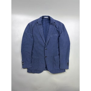 May include: A blue blazer featuring a notched lapel, two-button front closure, and two patch pockets at the waist. The garment includes a single chest pocket, long sleeves with four buttons at each cuff, and visible stitching along the edges.
