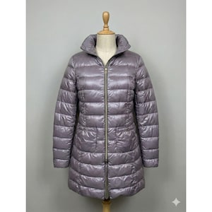 Puede incluir: Una taza de cerámica blanca con un asa negra y el texto "But First, Coffee" en negrita negra. La taza está sobre un fondo borroso. La taza mide aproximadamente 10 cm de altura.