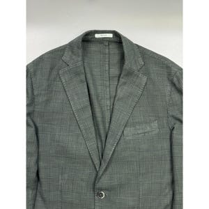 May include: A dark gray blazer featuring a subtle black plaid pattern, notched lapels, a single-button front closure, and a chest pocket. The interior collar label displays the text Boggi Milano in black lettering on a white background.