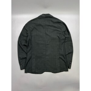 May include: A dark gray blazer featuring a subtle black plaid pattern, a notched lapel, and long sleeves with three small black buttons on each cuff. The garment is shown from the back, displaying a center seam and a structured tailored fit.