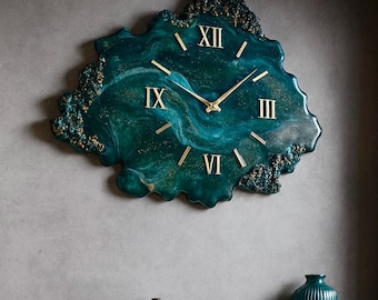 Puede incluir: Un reloj de pared turquesa con detalles dorados y números romanos cuelga de la pared. La forma irregular y la combinación de colores del reloj combinan con los jarrones turquesa y el sofá de terciopelo verde. Una escultura dorada está en la mesa de centro.