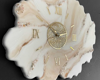 May include: A white and beige resin clock with gold Roman numeral hour markers and a gold metal clock face. The clock is shaped like a flower and has small clear crystals embedded in the resin.