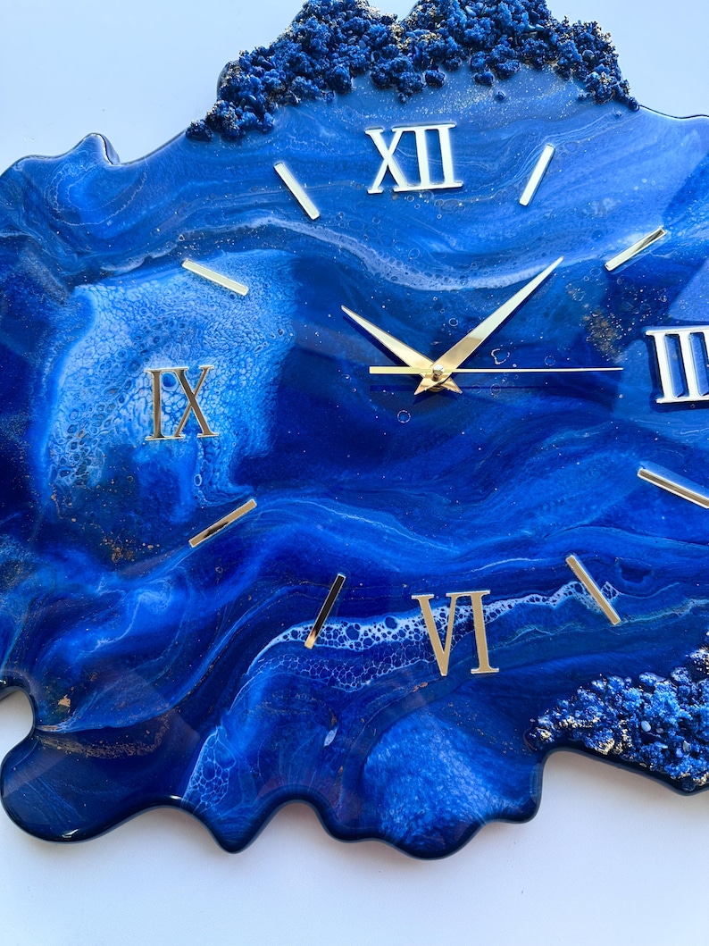 May include: Blue and gold resin clock with Roman numeral markings. The clock face is a swirling blue and white abstract design with gold accents.