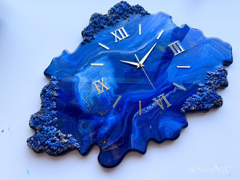 May include: Blue and gold resin wall clock with Roman numeral markings. The clock face is a unique abstract design with blue and gold swirls.