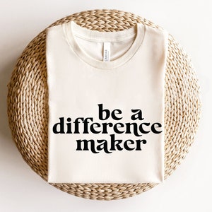 May include: A white t-shirt with the text "be a difference maker" printed in black.