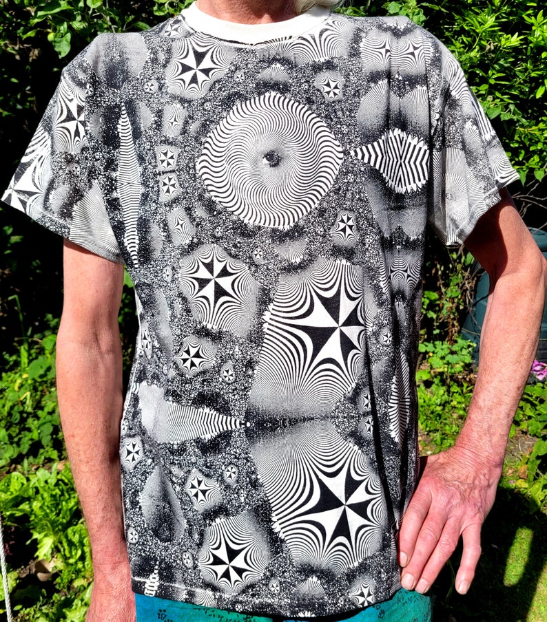 May include: A black and white t-shirt with a psychedelic pattern of swirling circles and stars.