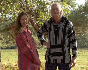 May include: Two people wearing colourful striped hooded sweatshirts stand in a wooded area. The person on the left is wearing a red, pink and white striped hooded sweatshirt. The person on the right is wearing a black and white striped hooded sweatshirt.