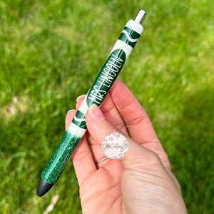 May include: Green glitter pen with a white crayon design and the text "Mrs. Lincoln" printed on it.