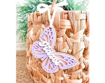 May include: A purple butterfly-shaped wooden ornament with the word "Grandma" cut out in white. The ornament is hanging from a woven basket.
