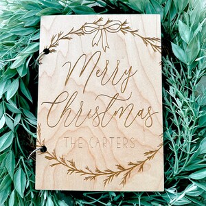Pu&ograve; includere: Un cartello di legno con un design a corona di Natale e il testo "Merry Christmas The Carters".