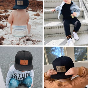 May include: Four black baseball caps with brown leather patches featuring different names. The names on the patches are "Ryder", "Oakley", "Luca", and "Oakley".