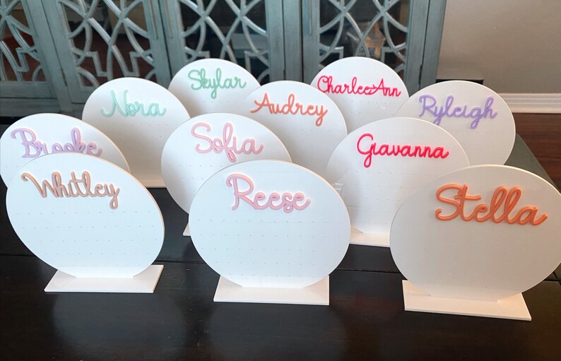 May include: Ten white circular earring display stands with different names written in colourful 3D lettering. The names are: Brooke, Whitley, Nora, Skylar, Sofia, Reese, Audrey, Charlee Ann, Gavanna, Ryleigh, and Stella.