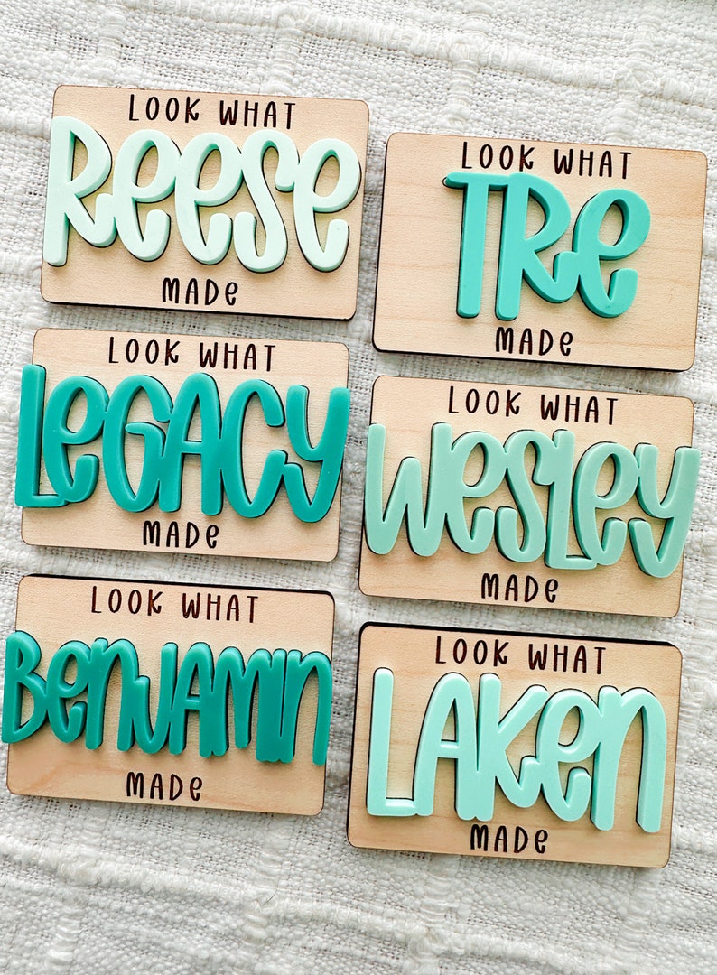May include: Six wooden plaques with names in teal and light green, including "Reese," "Tre," "Legacy," "Wesley," "Benjamin," and "Laken." Each plaque has the text "Look What Made" in black.
