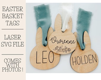 May include: Three wooden bunny-shaped Easter basket tags with the names "Leo", "Vivienne", and "Holden" engraved on them. The tags are decorated with a floral design and are tied with blue and white ribbon.