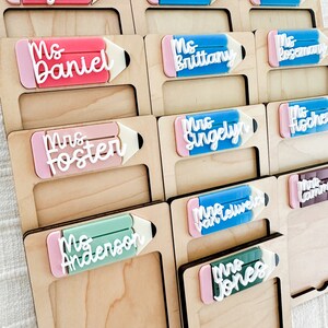 May include: A set of 10 wooden name tags with pencil-shaped frames. Each frame has a different color and features a name in white lettering. The names include: Ms. Taylor, Ms. Rosemary, Ms. Sunmon, Ms. Daniel, Ms. Brittany, Ms. Rosemary, Mrs. Foster, Mrs. Singelyn, Ms. Anderson, Mrs. Jones.