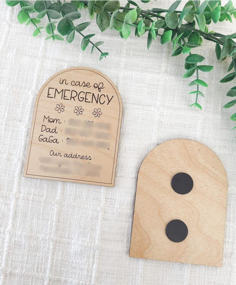 May include: Wooden arch-shaped sign with the text "in case of EMERGENCY" and spaces to write contact information for Mom, Dad, and Gaga, along with an address. The back of the sign has two black magnets.