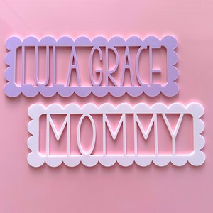 May include: Two decorative wooden signs with scalloped edges. The top sign is lavender and says "Lula Grace". The bottom sign is white and says "Mommy".