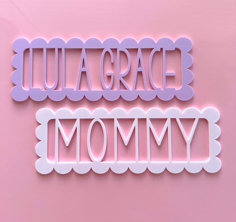 May include: Two decorative wooden signs with scalloped edges. The top sign is lavender and says "Lula Grace". The bottom sign is white and says "Mommy".