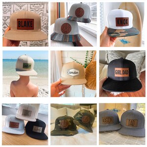 May include: A collection of personalized baseball caps with various colors and designs. The caps feature leather patches with names like "Blake", "Knox", "Camden", "Girl Dad", "Kason", and "Dad".