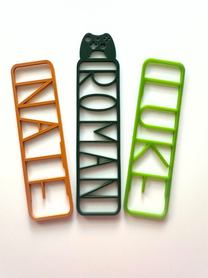 May include: Three colourful bookmarks with cut-out letters spelling "NAIL", "ROMAN", and "LURE". The "ROMAN" bookmark has a small game controller at the top.