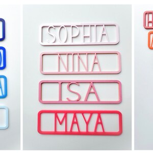 May include: A set of colourful personalised name plaques with various names including Jake, Alequinto, Samantha, Olivia, Sophia, Nina, Isa, Maya, Harrison, Alexander, Harry, Sebastian, Alequinto, and Jake.