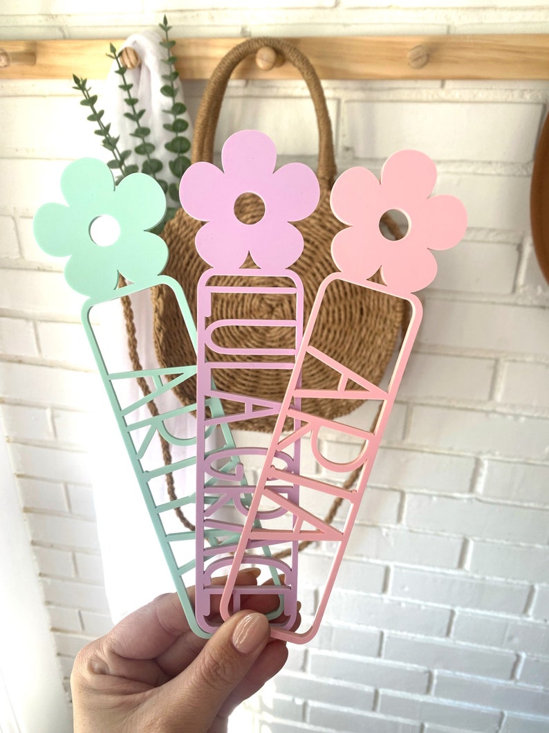 May include: Three colourful bookmarks with flower accents. Each bookmark features a different name: "Grace", "Ari", and "Kaylee".