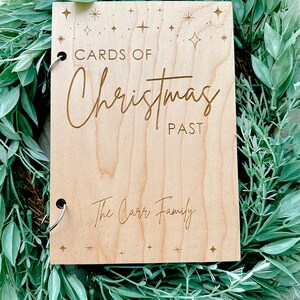 Pu&ograve; includere: Un album fotografico in legno con una finitura marrone chiaro. La copertina &egrave; incisa con il testo "Cards of Christmas Past" e "The Carr Family". La copertina &egrave; decorata con piccole stelle.