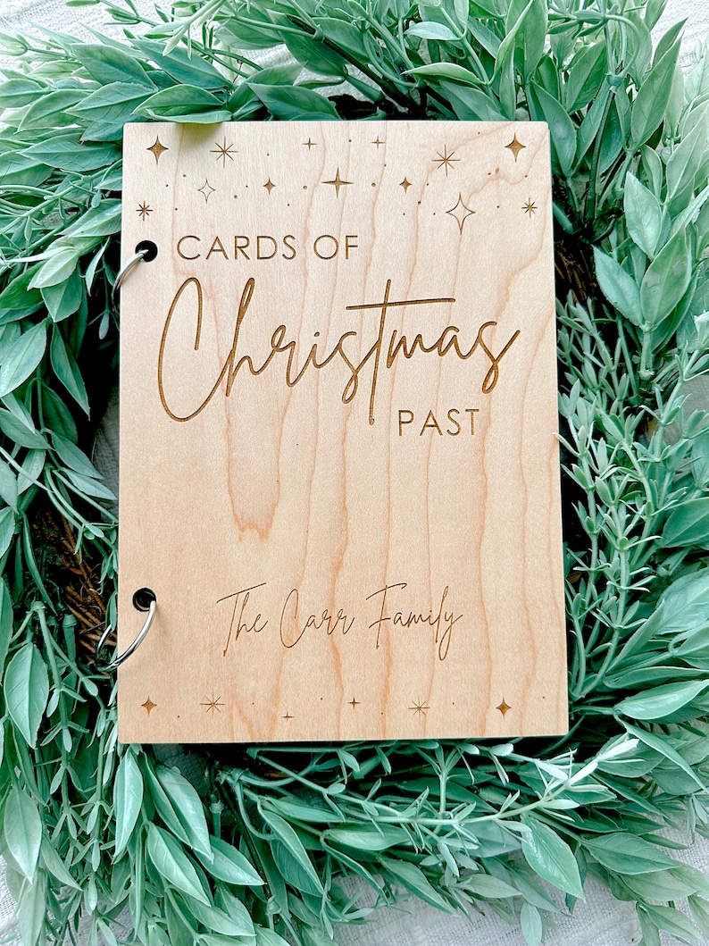 Pu&ograve; includere: Un album fotografico in legno con una finitura marrone chiaro. La copertina &egrave; incisa con il testo "Cards of Christmas Past" e "The Carr Family". La copertina &egrave; decorata con piccole stelle.
