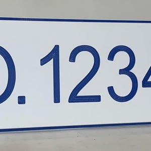 May include: A rectangular white sign with a blue border and the text "NO. 1234567" in blue. The sign has a clean, modern design and is likely used for displaying an address or number.