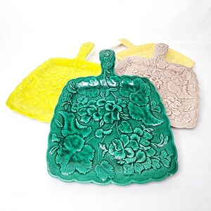 May include: Three ceramic serving trays in the shape of leaves with floral designs. The trays are green, yellow, and beige.