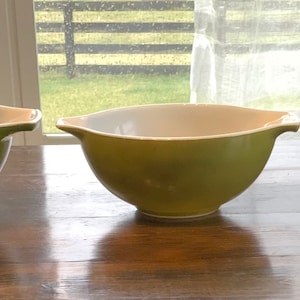 May include: Three green mixing bowls of different sizes. The bowls are made of glass and have a white interior.